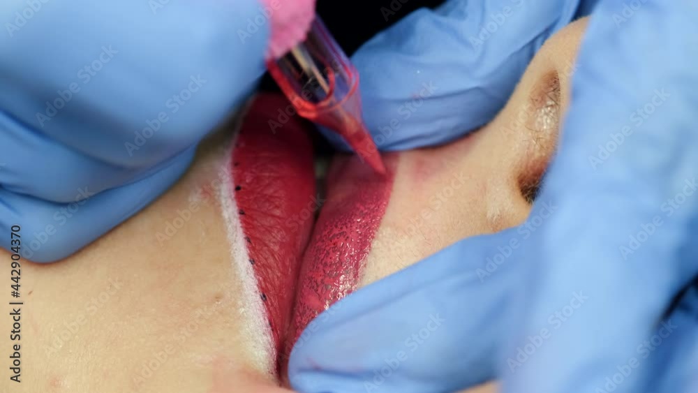 Micro pigmentation of lips process. Female permanent make up master holding machine applying pigment of woman client lips. Beauty and aesthetic treatment concept
