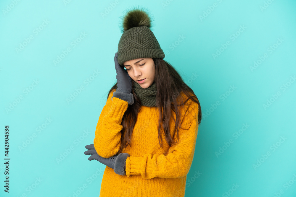 Young French girl isolated on blue background with winter hat with headache Young French girl isolated on blue background with winter hat with headache