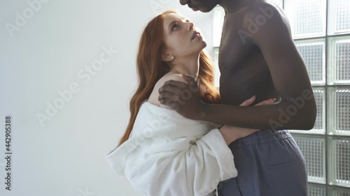 Portrait of diverse man and woman in love, feeling tenderness and awe for each other. Young couple of different races hug each other