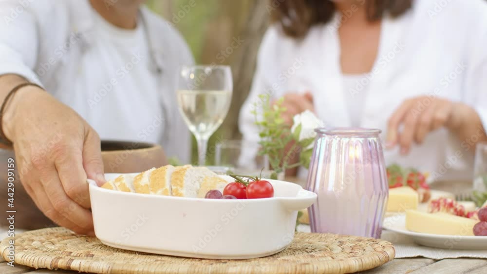 Close Up Shot of Middle Aged Couple Eating Bread During Alfresco Dinner Close Up Shot of Middle Aged Couple Eating Bread During Alfresco Dinner