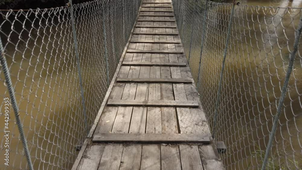 Old pedestrian suspension bridge over the river in the countryside Old pedestrian suspension bridge over the river in the countryside