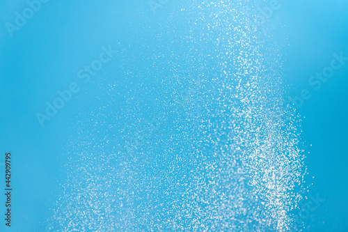 White powder splash isolated on blue background. Flour sifting on a blue background. Explosive powder white