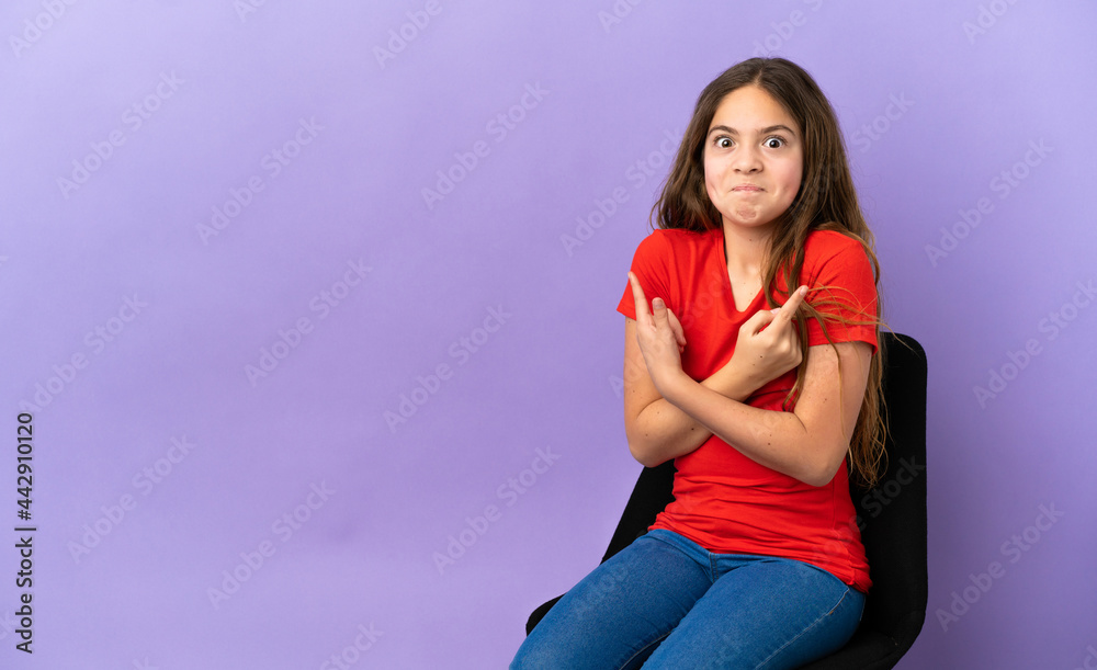 Little caucasian girl sitting on a chair isolated on purple background pointing to the laterals having doubts