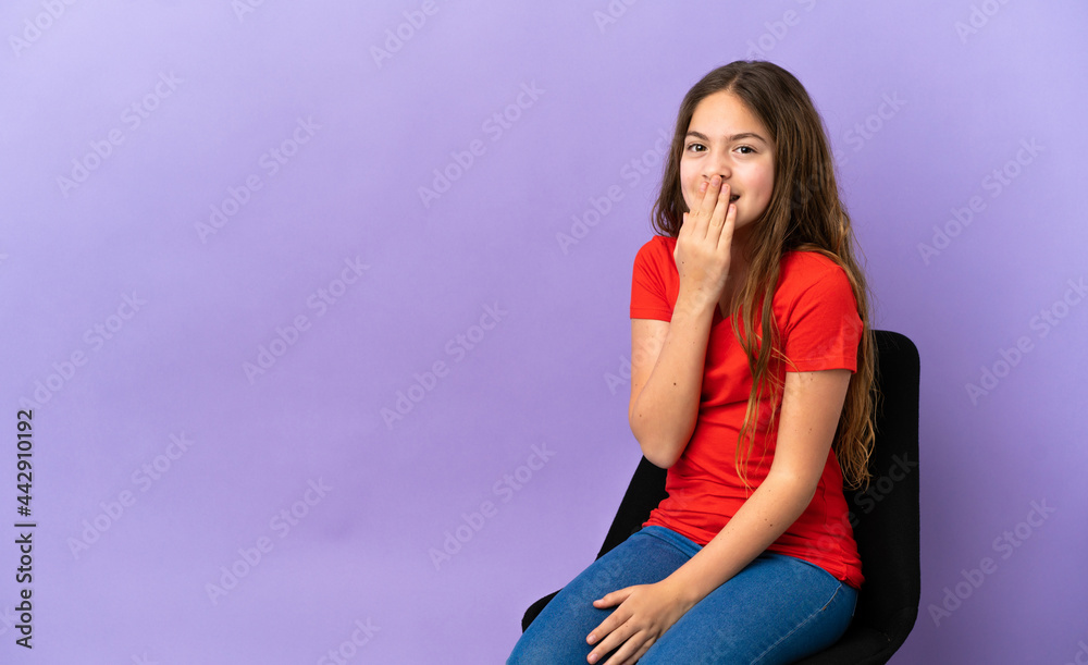Little caucasian girl sitting on a chair isolated on purple background happy and smiling covering mouth with hand Little caucasian girl sitting on a chair isolated on purple background happy and smiling covering mouth with hand