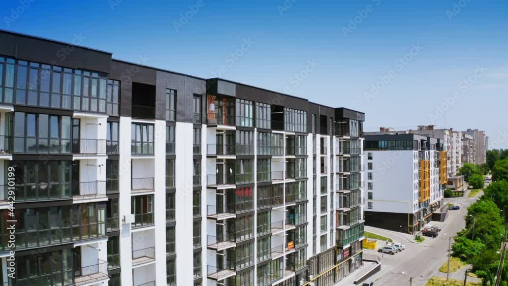 New highrise building in the city street. Modern design of newly built apartment building with large glassed balconies on urban background. View from the air.