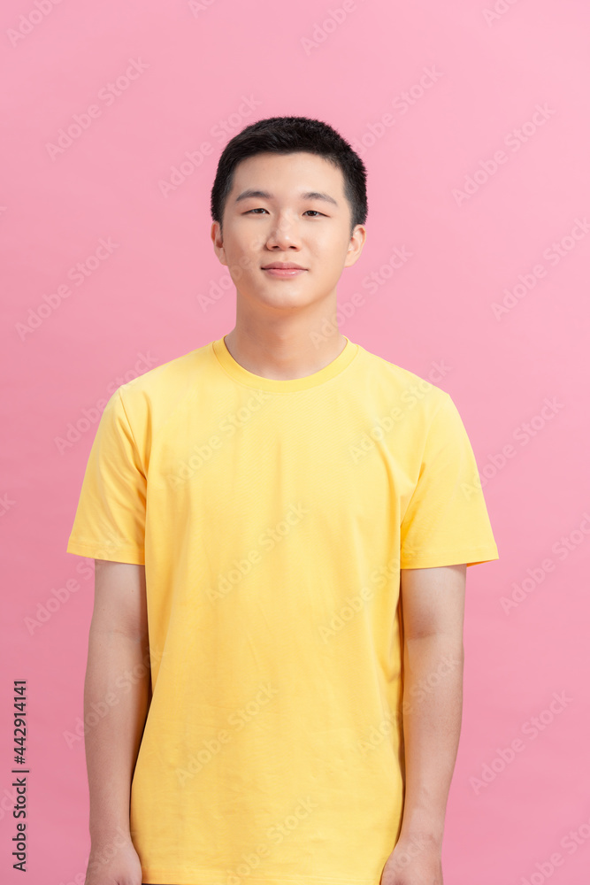 A man with a yellow t-shirt standing looking at the camera