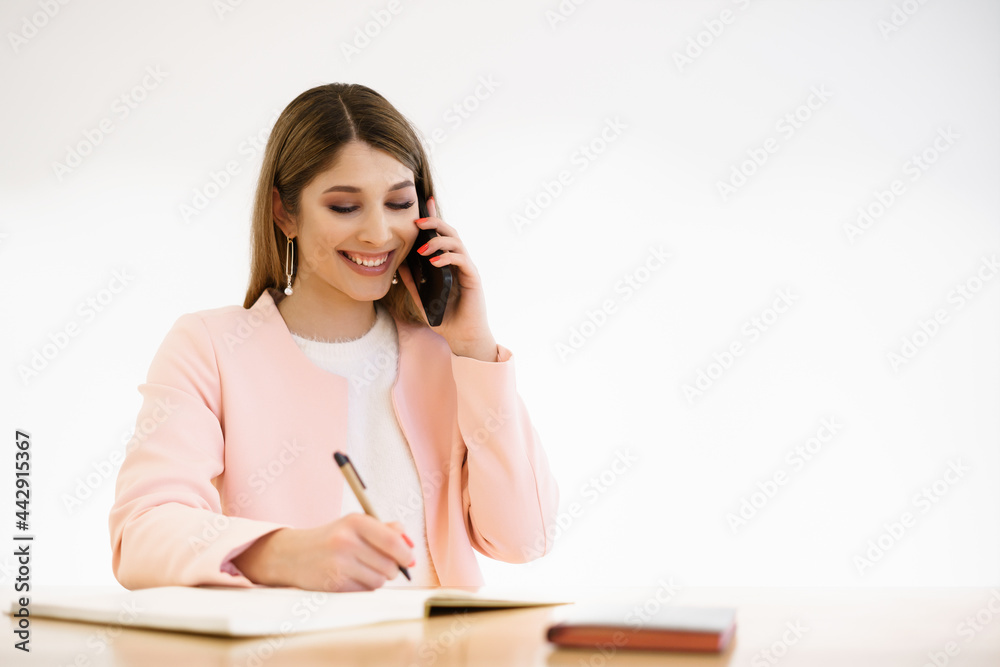 Buinesswoman with candid smile chatting by phone and enjoying coffee break in cafe . Wearing casual white sweater pink jaket Buinesswoman with candid smile chatting by phone and enjoying coffee break in cafe . Wearing casual white sweater pink jaket