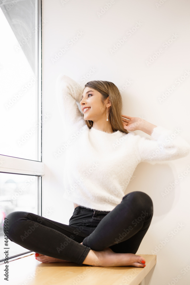 Portrait of smiling attractive young female getting inspired with sunny weather sitting in modern cafe interior near window looking away Portrait of smiling attractive young female getting inspired with sunny weather sitting in modern cafe interior near window looking away