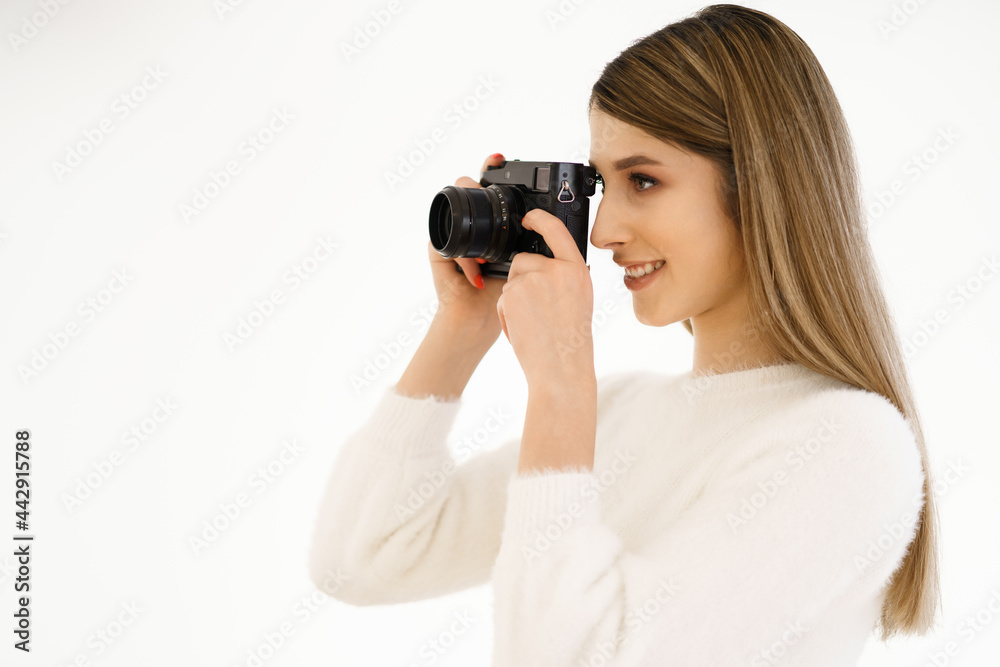 Beautiful Hipster woman taking photos with black retro film camera on white background. Close up. Indoor. Warm color. Blogger Beautiful Hipster woman taking photos with black retro film camera on white background. Close up. Indoor. Warm color. Blogger