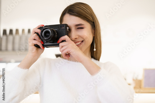 Portrait of beautiful photographer woman working in office holding camera with laptop. Bloger freelance online marketing.