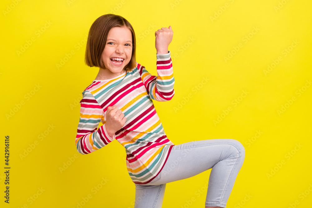 Profile photo of astonished short hairdo small girl hands fists yell wear colorful shirt isolated on vivid yellow color background Profile photo of astonished short hairdo small girl hands fists yell wear colorful shirt isolated on vivid yellow color background