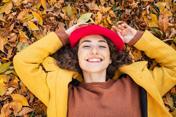 Smiling woman lying on autumn leaves