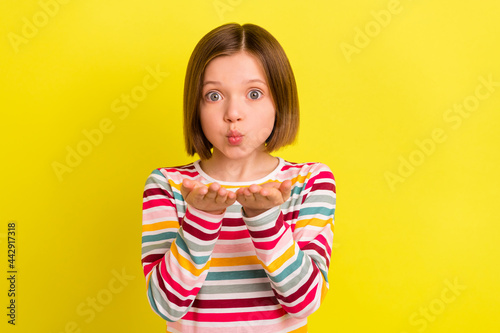 Photo of charming young happy positive girl send air kiss you hand cute face isolated on yellow color background