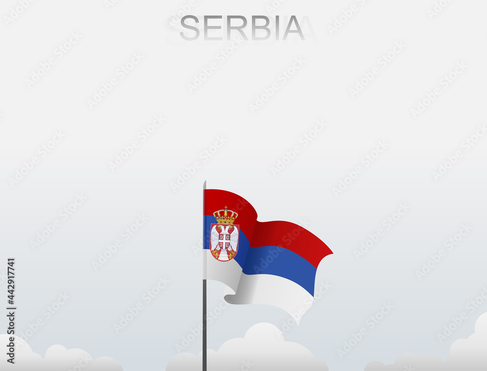 Serbian flag flutters on a pole standing tall under a white sky Serbian flag flutters on a pole standing tall under a white sky