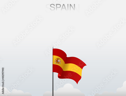 Spain flag flutters on a pole standing tall under a white sky