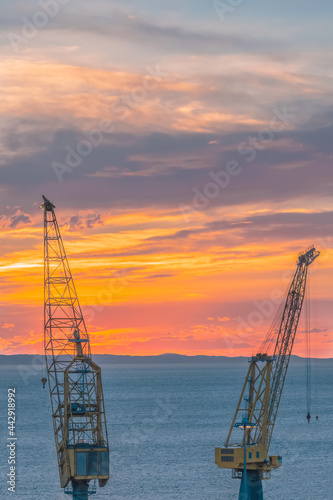 Tramonto con primo piano le gru del cantiere