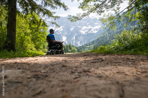 Canvas Print Man on a wheelchair relaxing in nature and looking at mountains on a sunny summer day