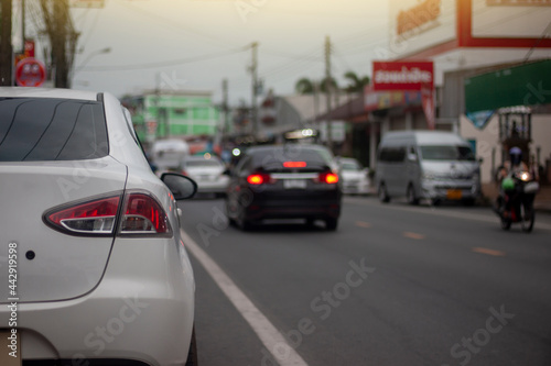 A white car parked on the side of the road on the city streets in the evening. © Pannarai
