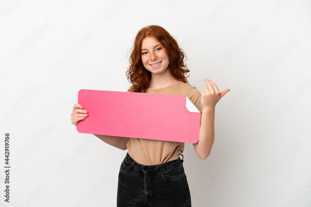 Teenager redhead girl isolated on white background holding an empty placard and doing coming gesture Teenager redhead girl isolated on white background holding an empty placard and doing coming gesture