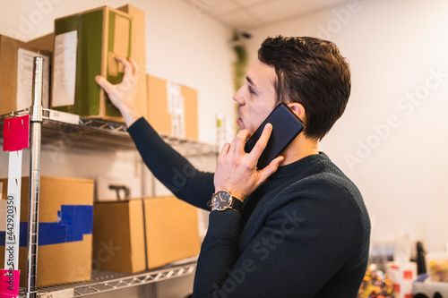 Man pratar i telefon och tar paket från hylla photo