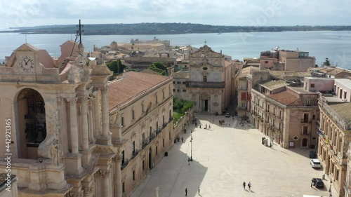 Beautiful drone view of Siracusa Dome Square with a priest statue and the blue mediterranean sea in the back, with a lovely summer day in Sicily, Italy.
