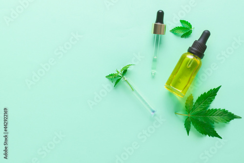 Cannabis oil in bottle hemp oil and cannabis leaves at green background. Top view, copy space.