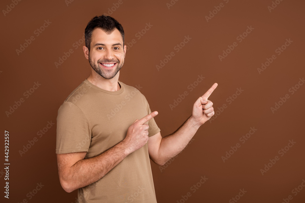 Photo portrait brunet man wearing pastel t-shirt showing finger empty space isolated brown color background Photo portrait brunet man wearing pastel t-shirt showing finger empty space isolated brown color background