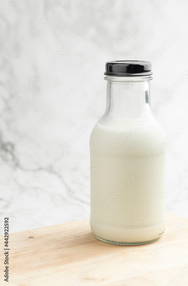 A bottle of milk on a wooden table with light granite background. A bottle of milk on a wooden table with light granite background.