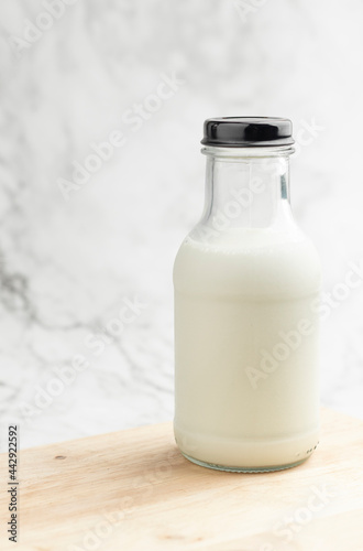 A bottle of milk on a wooden table with light granite background.