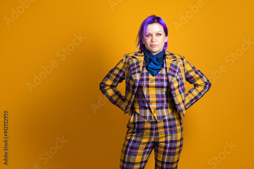young woman with purple hair in a stylish bright plaid suit.