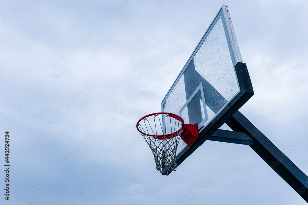 Glass Basketball backboard Hoop rain wet against gray cloudy sky