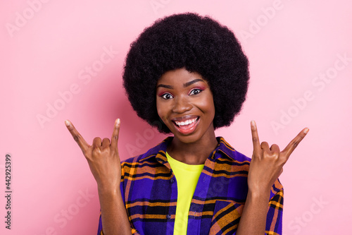 Portrait of attractive cheerful funky girl showing horn symbol having fun isolated over pink pastel color background