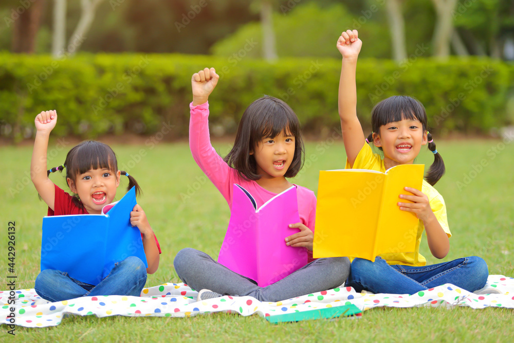 Cute little girl reading books on the grass. She has a look of enjoyment on her face and she looks very relaxed. Which increases the development and enhances learning skills outside the room. Cute little girl reading books on the grass. She has a look of enjoyment on her face and she looks very relaxed. Which increases the development and enhances learning skills outside the room.