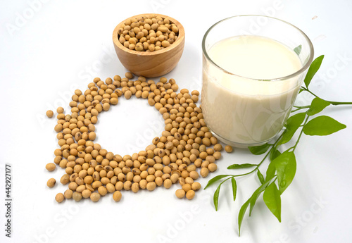 Soybean in wooden bowl and soy milk in glass with leaves, isolated on white background.