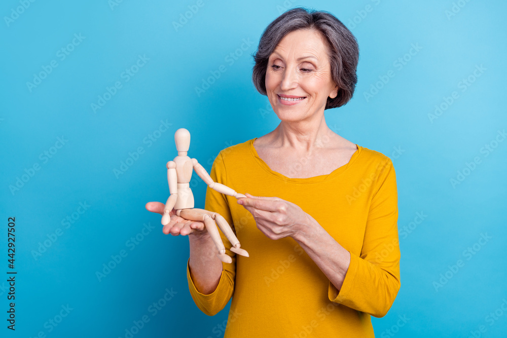 Portrait of attractive cheerful woman holding in hands wooden doll playing game isolated over bright blue color background Portrait of attractive cheerful woman holding in hands wooden doll playing game isolated over bright blue color background