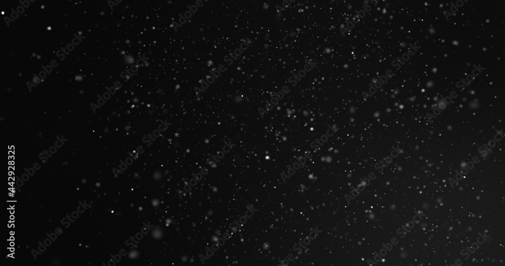 Defocussed white particles floating on a black background