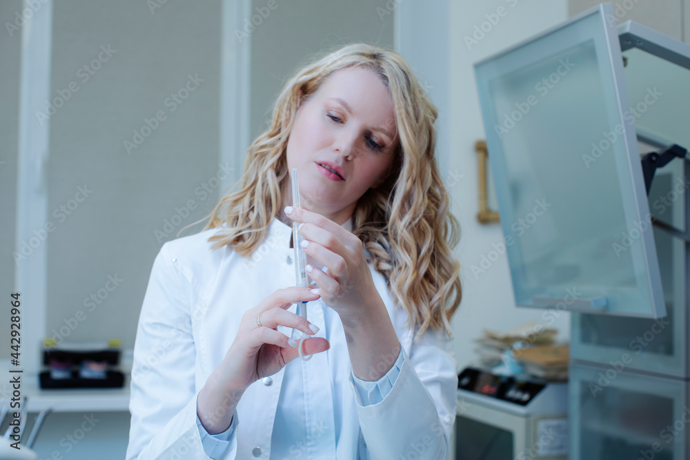Nice doctor woman in a white coat and blue medical gloves, holding a syringe with vaccine in a solution in front of him Nice doctor woman in a white coat and blue medical gloves, holding a syringe with vaccine in a solution in front of him