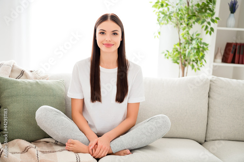 Portrait of attractive cheery girl sitting on divan resting good morning day at light home house indoors flat