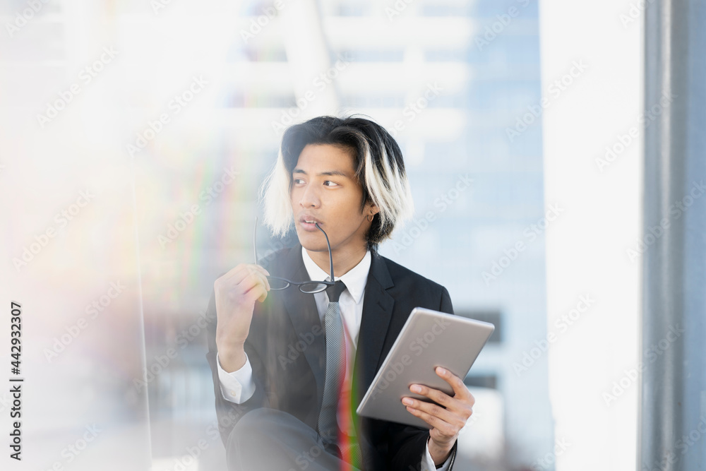 Stylish Asian businessman with tablet on urban street Stylish Asian businessman with tablet on urban street