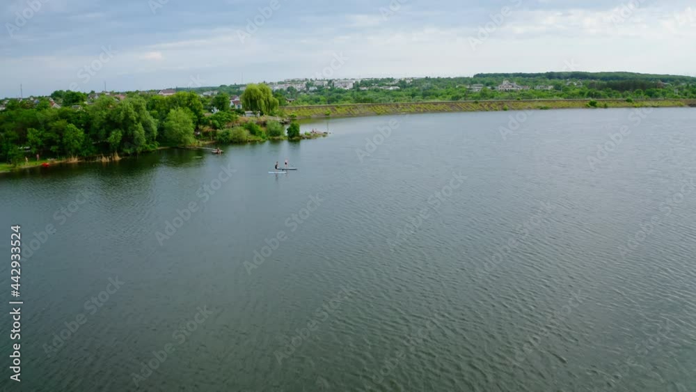 People swimming on boat in summer. Young man and woman with kayakers on water in the river. Travel on stand up paddleboarding in lake. Aerial view. People swimming on boat in summer. Young man and woman with kayakers on water in the river. Travel on stand up paddleboarding in lake. Aerial view.