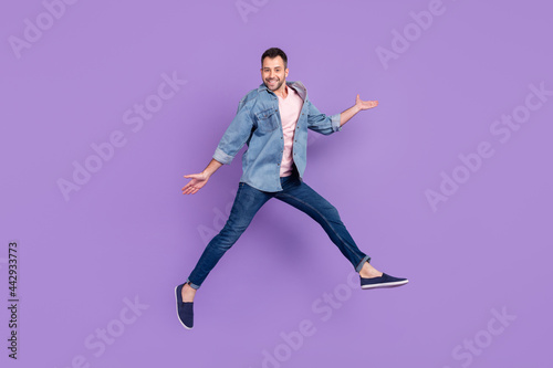 Full length body size photo man smiling jumping high cheerful funky isolated pastel violet color background © deagreez