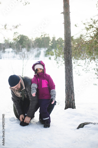 Pappa sitter på huk och hjälper dotter knyta skorna utomhus photo