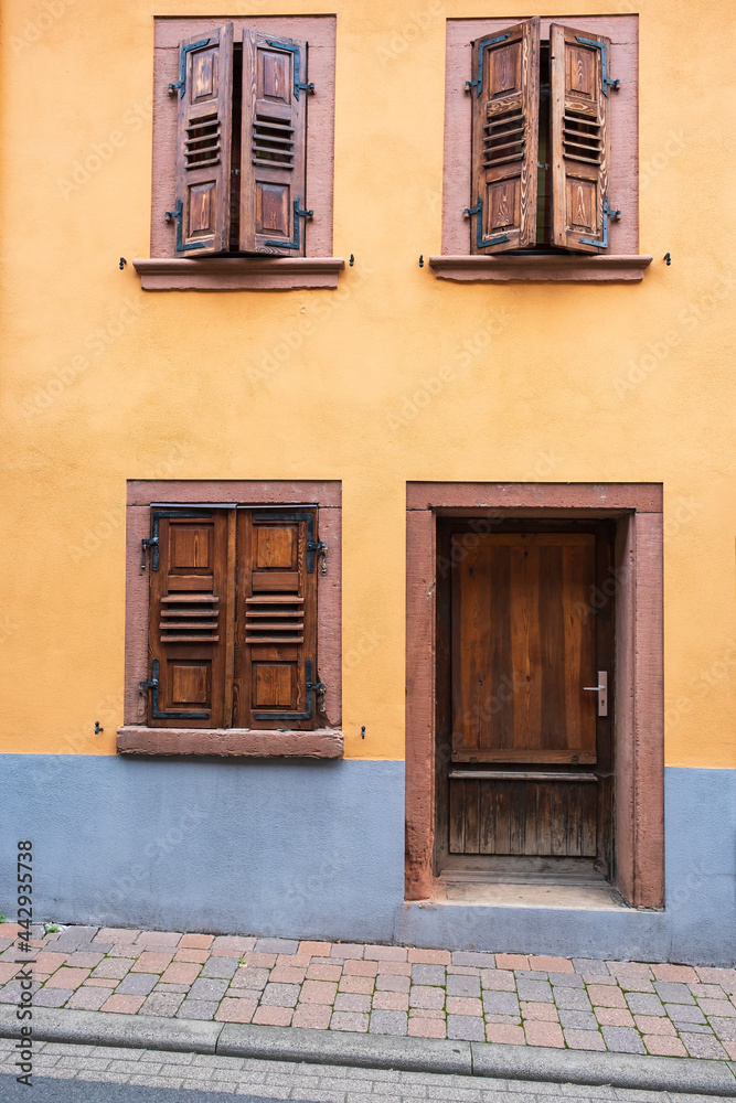 Fototapeta premium View of an orange house facade with closed wooden shutters 