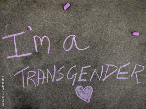 The inscription text on the grey board, I'm a transgender with hand drawn love symbol. Using color chalk pieces.