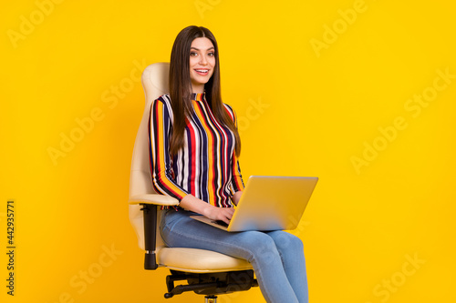 Photo of young business woman happy positive smile sit chair work laptop office isolated over yellow color background