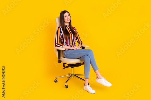 Full length body size photo girl sitting smiling in office chair isolated bright yellow color background © deagreez