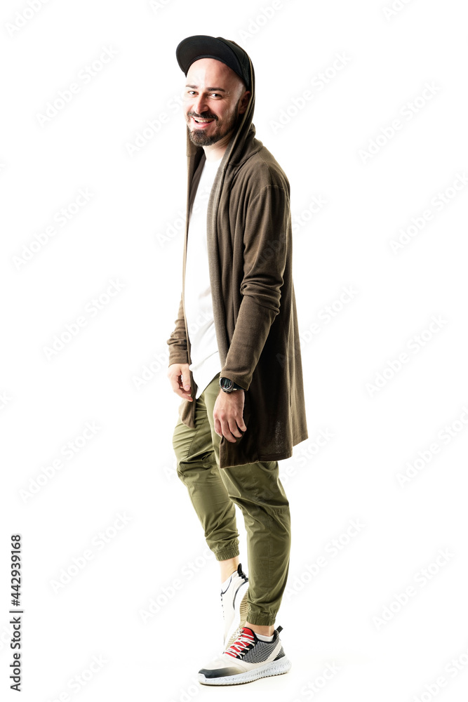 Side view of happy young hipster man in cardigan with cap and stylish clothes laughing. Full body portrait isolated on white background