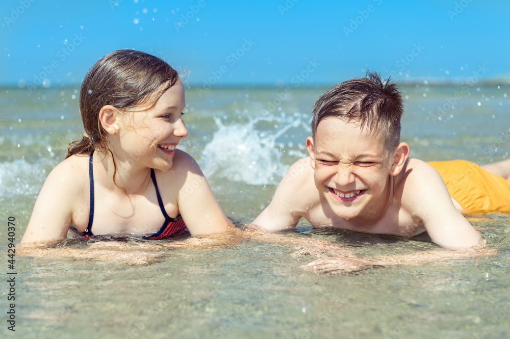 Portrait of two happy teen children liying in water of baltic sea beach at summer holidays Portrait of two happy teen children liying in water of baltic sea beach at summer holidays