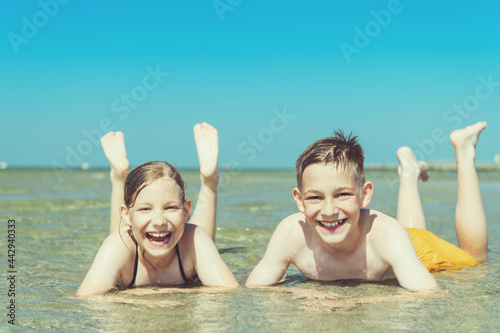 Portrait of two happy teen children liying in water of baltic sea beach at summer holidays