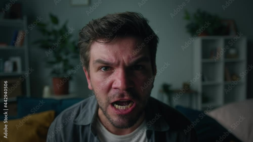 Irritated emotional man shouting, portrait of screaming brutal male person with beard, sitting on sofa in living room, looking in camera with furious view, feeling anger and stress, bad mood. Irritated emotional man shouting, portrait of screaming brutal male person with beard, sitting on sofa in living room, looking in camera with furious view, feeling anger and stress, bad mood.